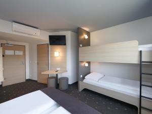 a bedroom with two bunk beds and a desk at B&B Hotel Berlin-Airport in Schönefeld