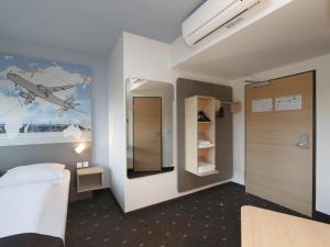 Habitación con 1 dormitorio con una pintura de un avión en la pared en B&B Hotel Berlin-Airport en Schönefeld