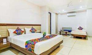 a large bedroom with a large bed and a chair at FabHotel Meera Palace in Indore