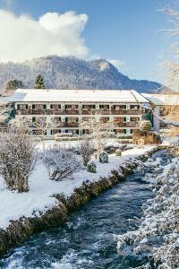 若特阿赫-埃根Spa & Resort Bachmair Weissach, LUXURY FAMILY RESORT的雪中河边的建筑物