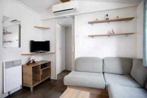 a living room with a couch and a tv at Bungalow T3 I I -15 Min From Nazaré in Pataias