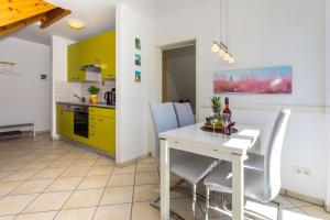 特拉森海德的住宿－Strandstrasse 21 Fewo 05，厨房以及带白色桌椅的用餐室。