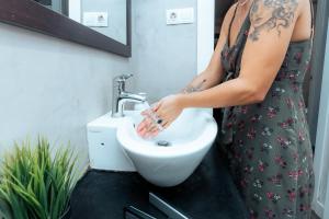 a woman in a dress washing her hands in a sink at Barcelona & You Hostel Sagrada Familia in Barcelona