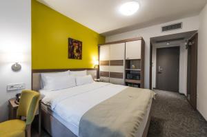 1 dormitorio con 1 cama grande y pared amarilla en Hotel Fontana Vrnjačka Banja en Vrnjačka Banja