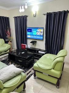 ein Wohnzimmer mit 2 Stühlen, einem Tisch und einem TV in der Unterkunft Mainstream Shortlet Apartments in Gbogije