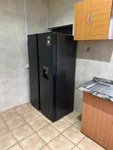 a black refrigerator in the corner of a kitchen at Mainstream Shortlet Apartments in Gbogije