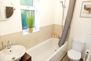 a bathroom with a tub and a toilet and a sink at 7 Persons Comfortable Guest House in Watford