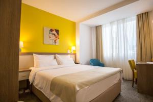 um quarto de hotel com uma cama e uma parede amarela em Hotel Fontana Vrnjačka Banja em Vrnjačka Banja