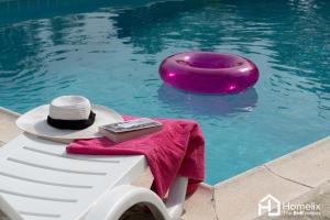 a hat sitting on a bench next to a swimming pool at Villa VERA - private villa for 8 guests with pool in Kymi