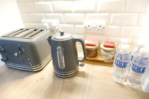 7 Persons Comfortable Guest House في واتفورد: وجود محمصة على كاونتر بجوار زجاجات المياه