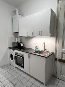 a white kitchen with a sink and a dishwasher at Charming Apartment close to Vienna Central Station in Vienna