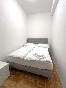 a bedroom with a bed with white sheets and wooden floors at Charming Apartment close to Vienna Central Station in Vienna