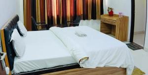 PrayagrajにあるMauji's Villa Hotel & Guest Houseのベッドルーム1室(白いベッド2台、デスク付)