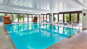 - une grande piscine avec des chaises dans un bâtiment dans l'établissement Hotel Zur Heidschnucke, à Asendorf