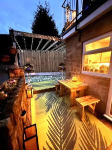 a patio with a wooden table and a bench at Wharfe View Cottage Ilkley in Ilkley