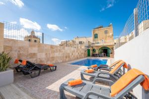 a pool with chaise lounge chairs and a swimming pool at Ta Kalang Holiday Home in Kerċem