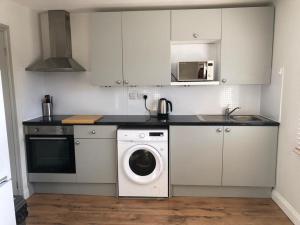 een keuken met een wasmachine en een wasmachine bij Fantastic large 1 bed Loft Flat close to Heathrow - 77VFR5 in Cranford