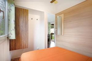 1 dormitorio con cama de color naranja y armario de madera en Bungalow T3 i i i - 15 Min Nazaré, en Pataias