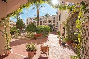 einem Torbogen mit Pflanzen und einer Bank im Innenhof in der Unterkunft Duquesa Suites Gardens ground floor close to Port, beach in Manilva