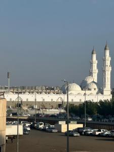شقق مطله على مسجد قباء في المدينة المنورة: مسجد كبير مع سيارات تقف في موقف للسيارات