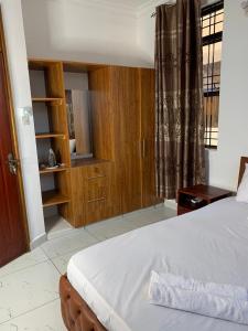 sypialnia z łóżkiem, drewnianymi szafkami i oknem w obiekcie Cozy 2 bedroom, master en-suite Apartment in Bamburi with secure environment WIFI Netflix and 10min drive to the beach w mieście Mombasa