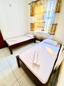 sypialnia z 2 łóżkami i oknem w obiekcie Cozy 2 bedroom, master en-suite Apartment in Bamburi with secure environment WIFI Netflix and 10min drive to the beach w mieście Mombasa