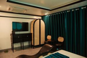 a bedroom with a bed and a tv and green curtains at Sky Hotel in Bắc Giang