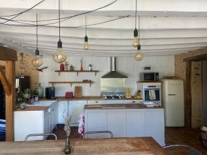 a kitchen with white cabinets and a table and lights at Maison de campagne authentique et chaleureuse in Fougerolles