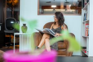 a woman sitting in a chair reading a book at Barcelona & You Hostel Sagrada Familia in Barcelona