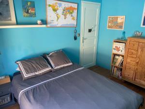 a bedroom with a bed and a blue wall at Maison de campagne authentique et chaleureuse in Fougerolles