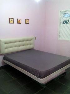 Cama en habitación con pared de color rosa en Residencial Bahia Sol, en Nova Viçosa
