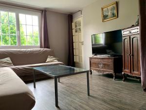 Chez Madame Titus في Ormoy-Villers: غرفة معيشة مع أريكة وطاولة قهوة زجاجية