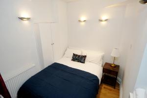 a small bedroom with a bed with a blue blanket at Cozy Retreat By Aresti Hotels in London