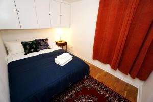 1 dormitorio con cama azul y cortina roja en Cozy Retreat By Aresti Hotels, en Londres