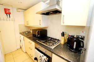 cocina con armarios blancos y fogones en Cozy Retreat By Aresti Hotels, en Londres