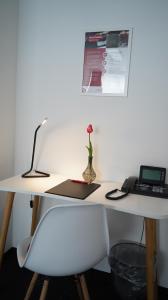 a white desk with a laptop and a vase with a flower at Amical Hotel Hagen - Am Hauptbahnhof in Hagen