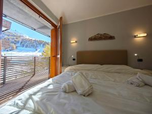 a bedroom with a bed and a large window at Hostdomus - Suite Les Etoiles in Sestriere