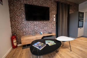 a living room with a table and a tv on a brick wall at O'Kub du Ried in Rossfeld