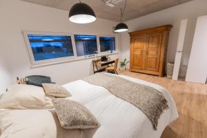 een slaapkamer met een groot wit bed en 2 ramen bij O'Kub du Ried in Rossfeld