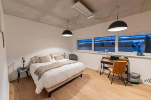 Schlafzimmer mit einem Bett, einem Schreibtisch und Fenstern in der Unterkunft O'Kub du Ried in Rossfeld