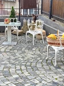 a patio with white chairs and tables and a cat at Casa Continentelor in Câmpulung