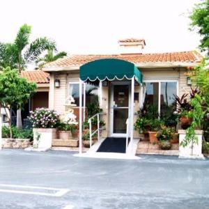 a house with a green awning in front of it at Parkview Motor Lodge in West Palm Beach