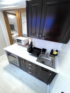 a kitchen with black cabinets and a sink at Baneasa Luxury Apartaments in Bucharest
