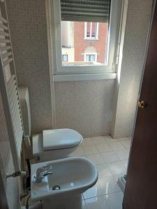 uma casa de banho com um WC, um lavatório e uma janela em Certosa District Apartment em Milão