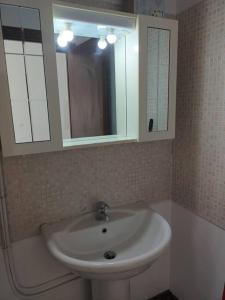 uma casa de banho com um lavatório branco e um espelho. em Certosa District Apartment em Milão