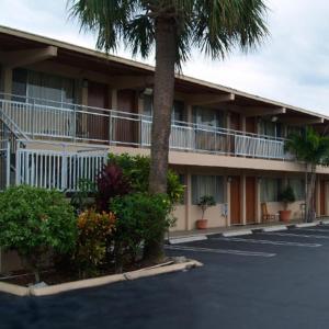 un bâtiment avec un palmier dans un parking dans l'établissement Parkview Motor Lodge, à West Palm Beach