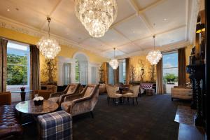 un grand salon avec des lustres, des chaises et des tables dans l'établissement Cameron House on Loch Lomond, à Balloch
