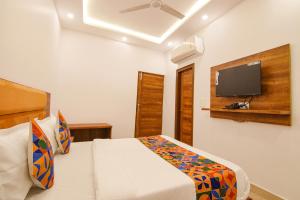 a bedroom with a bed and a flat screen tv at FabHotel Ambassador in Chandīgarh