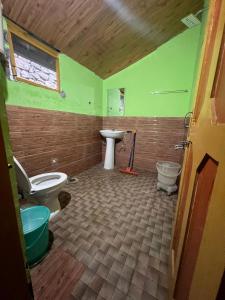 a bathroom with a toilet and a sink at Lee Garden Himalayan Wooden Cottages in Kasol