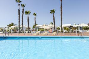 a swimming pool at a resort with palm trees at Jardin del sol 17 in Playa Blanca